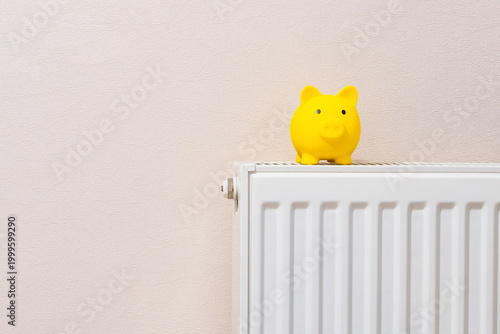 piggy bank on a home heating radiator for energy saving concept