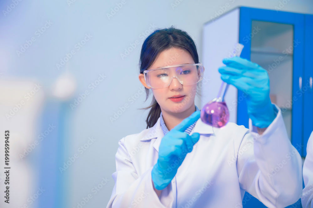 Fototapeta premium Asian woman chemist holding glassware testing liquid sample medical research and looking at purple chemical reaction laboratory glassware. Working clinical trial chemical analysis workspace.