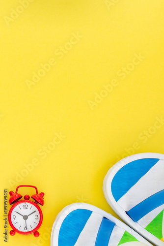 Time for vacation concept with retro alarm clock and beach shoes.