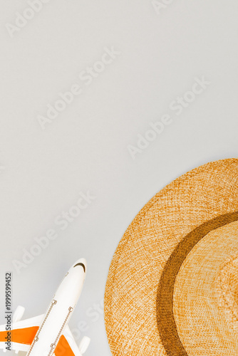 Summer vacation concept with straw hat and toy plane on blue background.