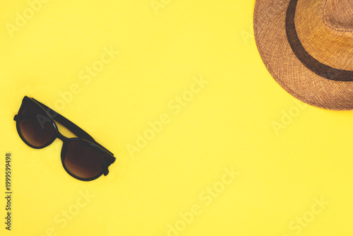 Summer beach essentials with sunglasses and straw hat on  backdrop.