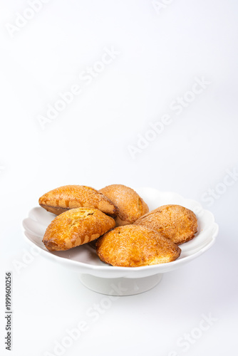 Golden cottage cheese pastries sochniki on a white decorative stand.