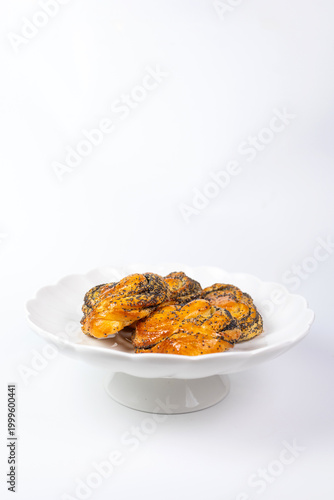Fresh golden poppy seed buns on a white decorative stand.