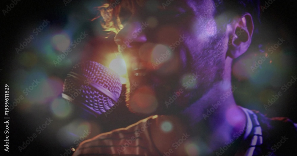 Fototapeta premium Male singer in striped shirt singing into handheld mic at concert, with backlight haze bokeh