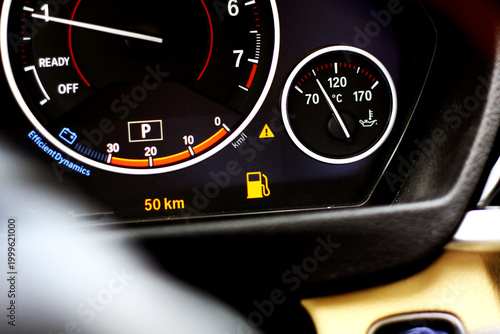 Car dashboard close up with low fuel warning light, empty tank indicator 
