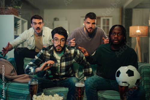 Принти на полотні Diverse male friends watching exciting football match at home, reacting with sus