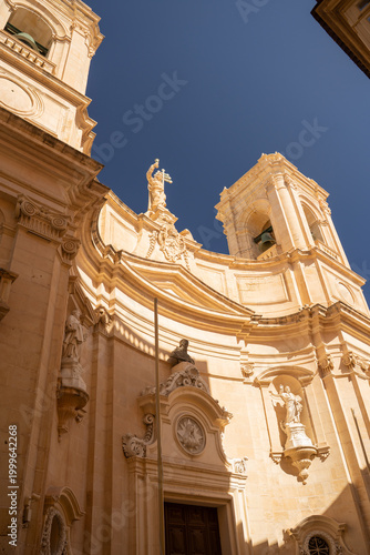 Vertical low angle view of St. Catherine of Italy church facade in Valletta. Baroque architecture and limestone statues in Malta.