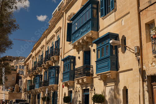Traditional blue wooden balconies on a limestone facade in Valletta. Iconic Mediterranean architecture of Malta.