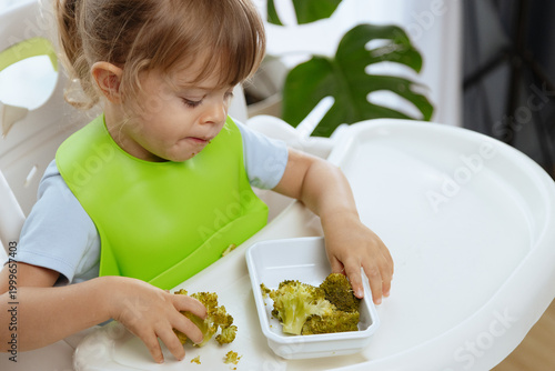 Cute little girl eating broccoli, vegetables for children as a source of vitamins, healthy lifestyle, vegetarian