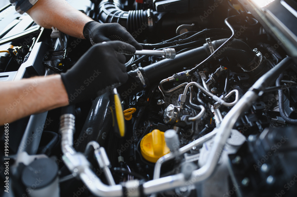 Fototapeta premium Mechanic servicing car engine using professional tools