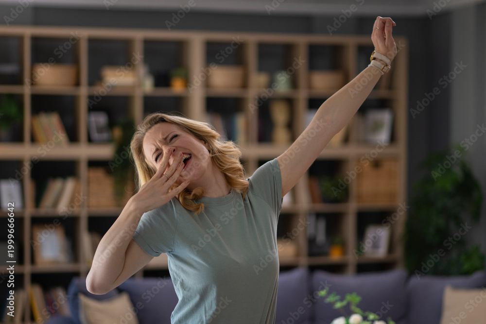 Fototapeta premium Woman yawning and stretching in living room after waking up