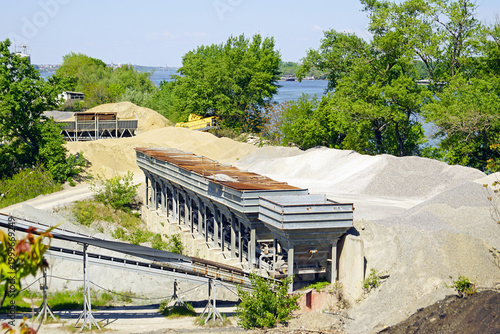 Obraz na płótnie Aggregate hoppers and sand piles, river and forested bank beyond