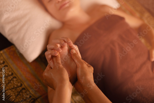 Tablou pe pânză Relaxing thai hand massage for female client with warm tones and soft linens