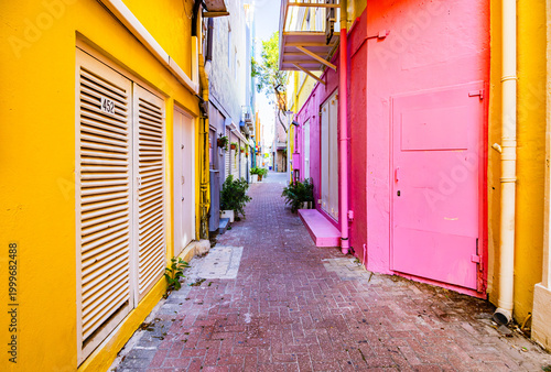 Narrow colorful alleyway with bright pink and yellow buildings on a sunny day in Willemstad Curacao