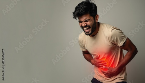 Young Indian man clutches stomach in pain. Red highlight shows abdominal discomfort. He suffers from a stomach ache or digestive issue. Medical concept for health problems.