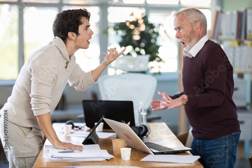 Tableau sur toile Men are standing on opposite sides of table and shouting at each other
