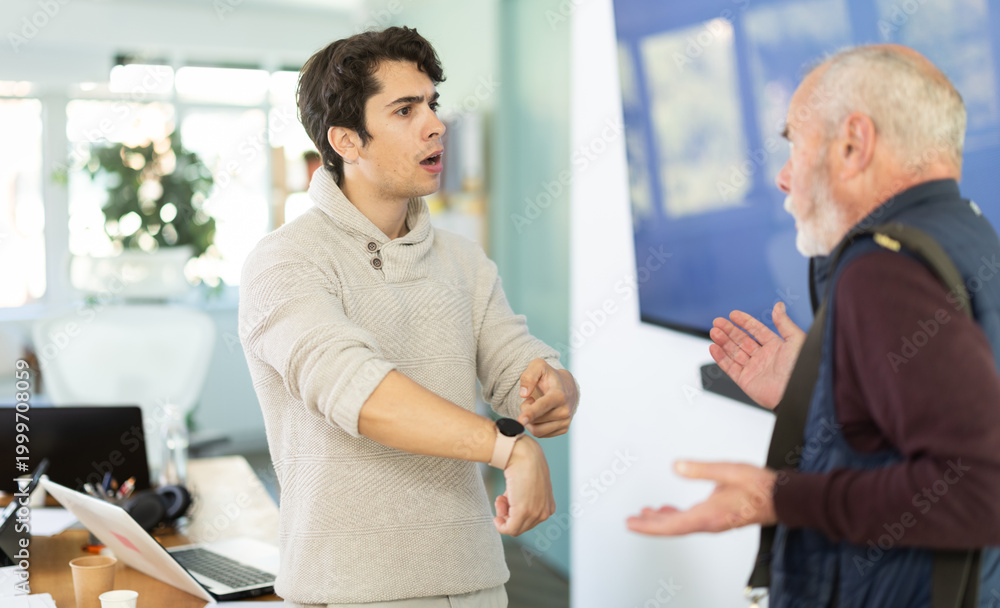 Fototapeta premium Upset senior man employee of company quits job, and guy manager shouts after him..Toxic relationships and abuse of office, unecological environment in team