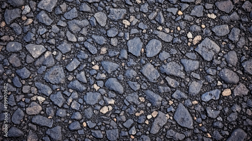 Close-up image of rough asphalt pavement with irregularly shaped stones embedded in dark tar.