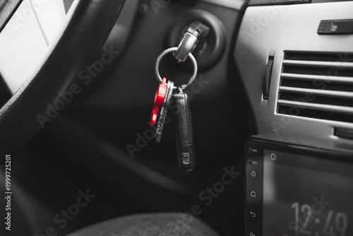 Keys with a plastic red key fob stick out in the ignition lock of the car. symbolic abstract photo. High quality photo