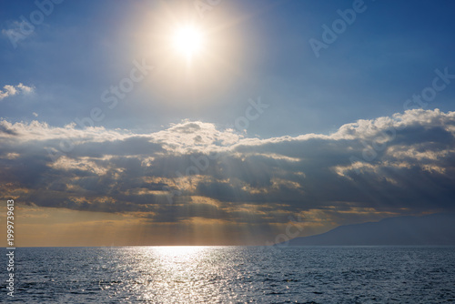 Sunlight rays piercing through clouds over calm sea