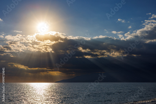 Bright sun shining through dark clouds over the sea