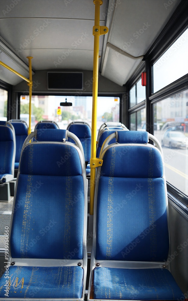 Fototapeta premium Empty bus interior with blue seats yellow poles and city view through