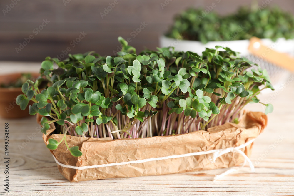 Fototapeta premium Fresh microgreens in container on wooden table, closeup