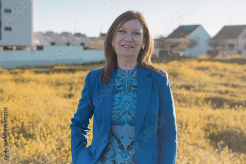 Confident Woman in Blue Blazer Standing in a Golden Field at Sunset