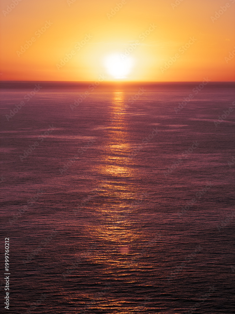 Obraz premium Sunrise over the ocean in purple and orange tones with copy space