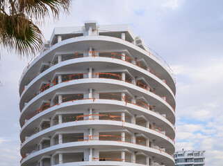 Curved architectural design of a modern building under a cloudy sky in an urban environment during the afternoon