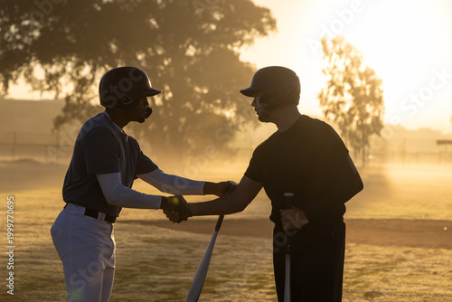 Photography Diverse male players wearing batting helmets clasping hands and holding bats on