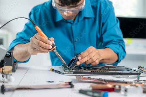Fotografie Technician repairing laptop motherboard with soldering iron