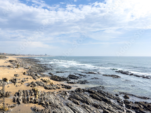 Rocky Shoreline at Praia da Granja with Ocean Waves and Cloudy Sky