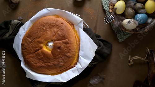 Freshly Baked Sponge Cake with Easter Eggs and Feathers in a Rustic Table Setting