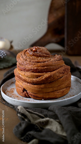 Artisanal Cinnamon Bun on White Plate with Dark Linen