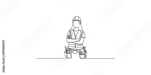 A confident female construction worker standing with arms crossed wearing a tool belt and hard hat