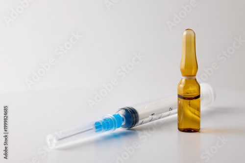 Sealed Amber Ampule Standing Next to Syringe