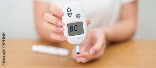 Photos Hand checking Diabetes or Blood glucose self testing by digital blood glucose meter with lancet pen