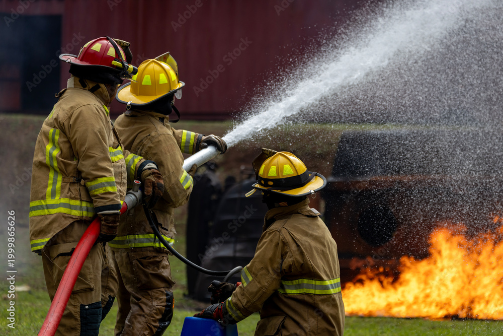 Naklejka premium Team of firefighter in fireproof cloth using fog watering hose to put out the burning crashing plane with high flame for fire extinguish risk rescue mission and accident