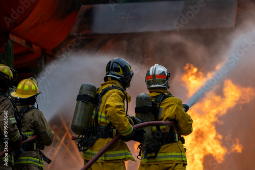 Team of firefighter in fireproof cloth using fog watering hose to put out the burning crashing plane with high flame for fire extinguish risk rescue mission and accident