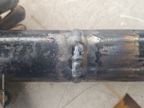 Close-up of pipe cover pass weld with visible welding defect on butt joint. Industrial metal fabrication inspection concept showing poor weld quality and repair requirement.