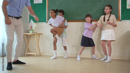 Diverse group of school children enjoying dance activity with teacher in an international classroom, encouraging active learning and teamwork