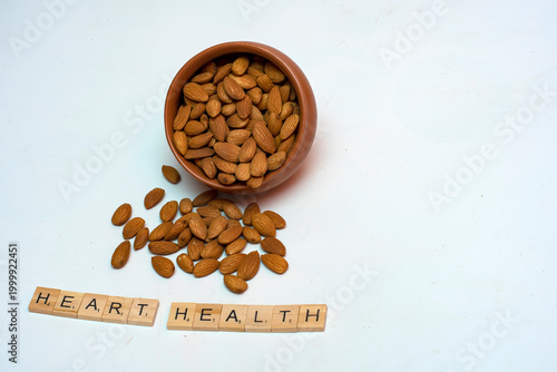Almonds in terracotta bowl with heart health message on light background