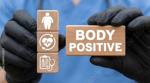 Wooden blocks with body positive text and health icons are held by a person in medical gloves