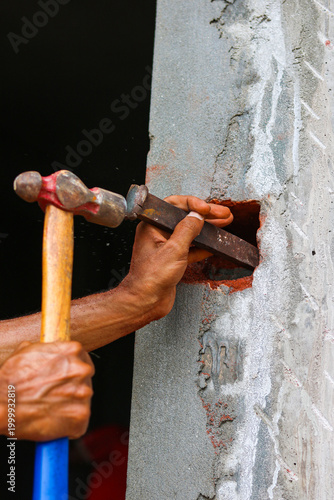 Construction Worker Hands Using Hammer and Chisel to Carve Concrete Wall
