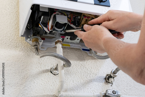 Billede på lærred Professional technician using a screwdriver to service and maintain a tankless g