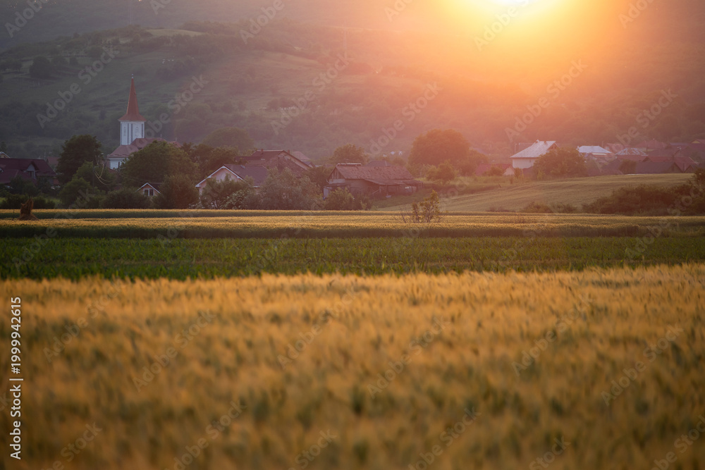 Fototapeta premium Village with a church steeple nestled in a valley, framed by rolling hills.