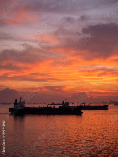 Tankers silhouettes on sunset with colorful sky and water reflection  