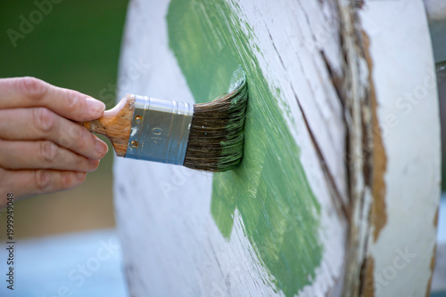 фотографія Painting a wooden furniture outdoors, an eco-friendly re-use business