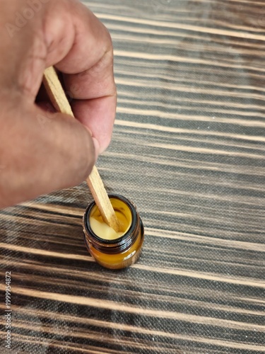 Taking Fresh Royal Jelly from Amber Jar with Wooden Stick